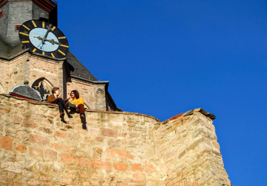 Two people sitting on the wall of Landgrafen Palace in Germany.